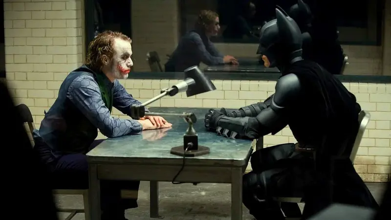 Batman faces the Joker across an interrogation table in The Dark Knight (2008)